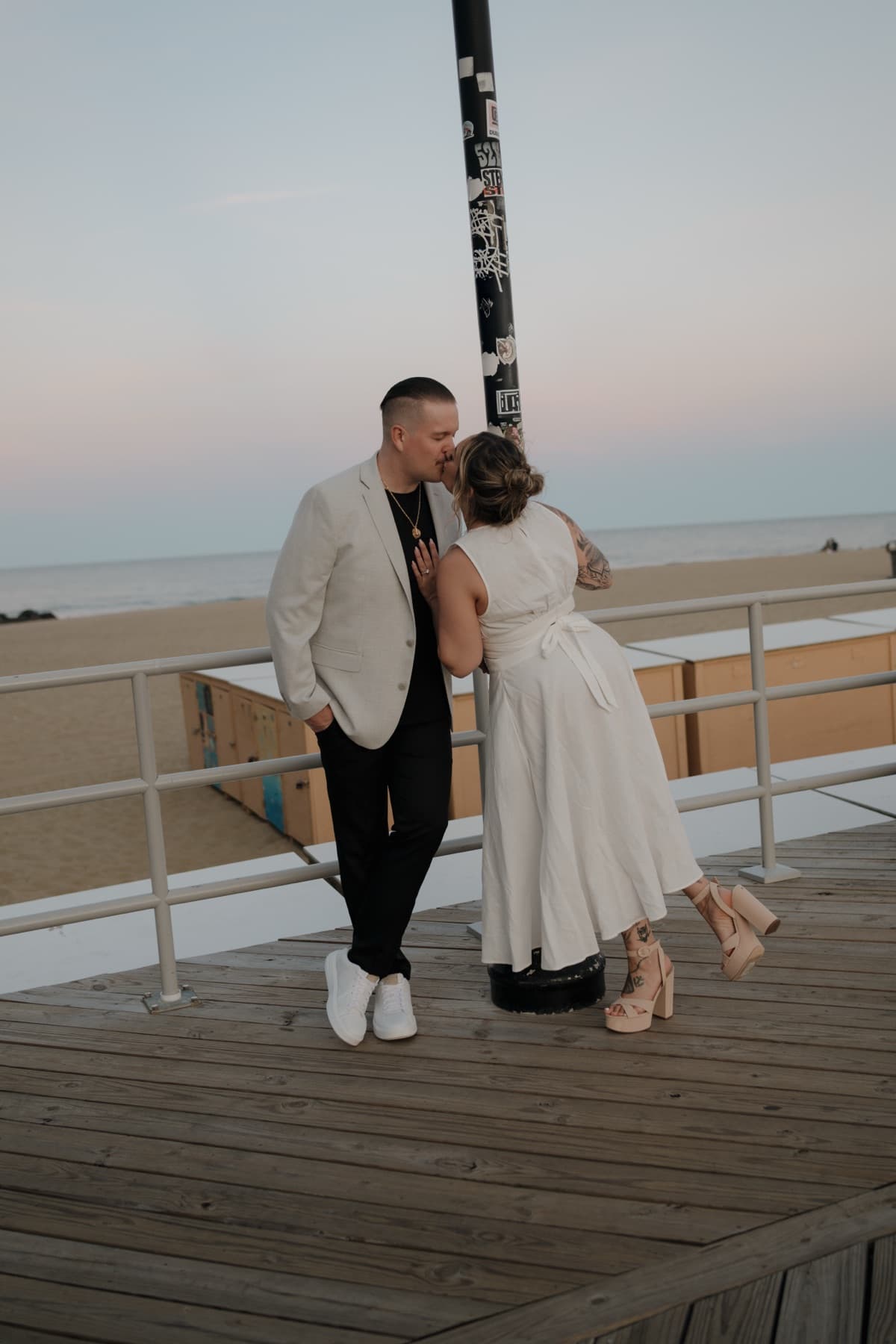 Couple kissing on a boardwalk by the beach at dusk