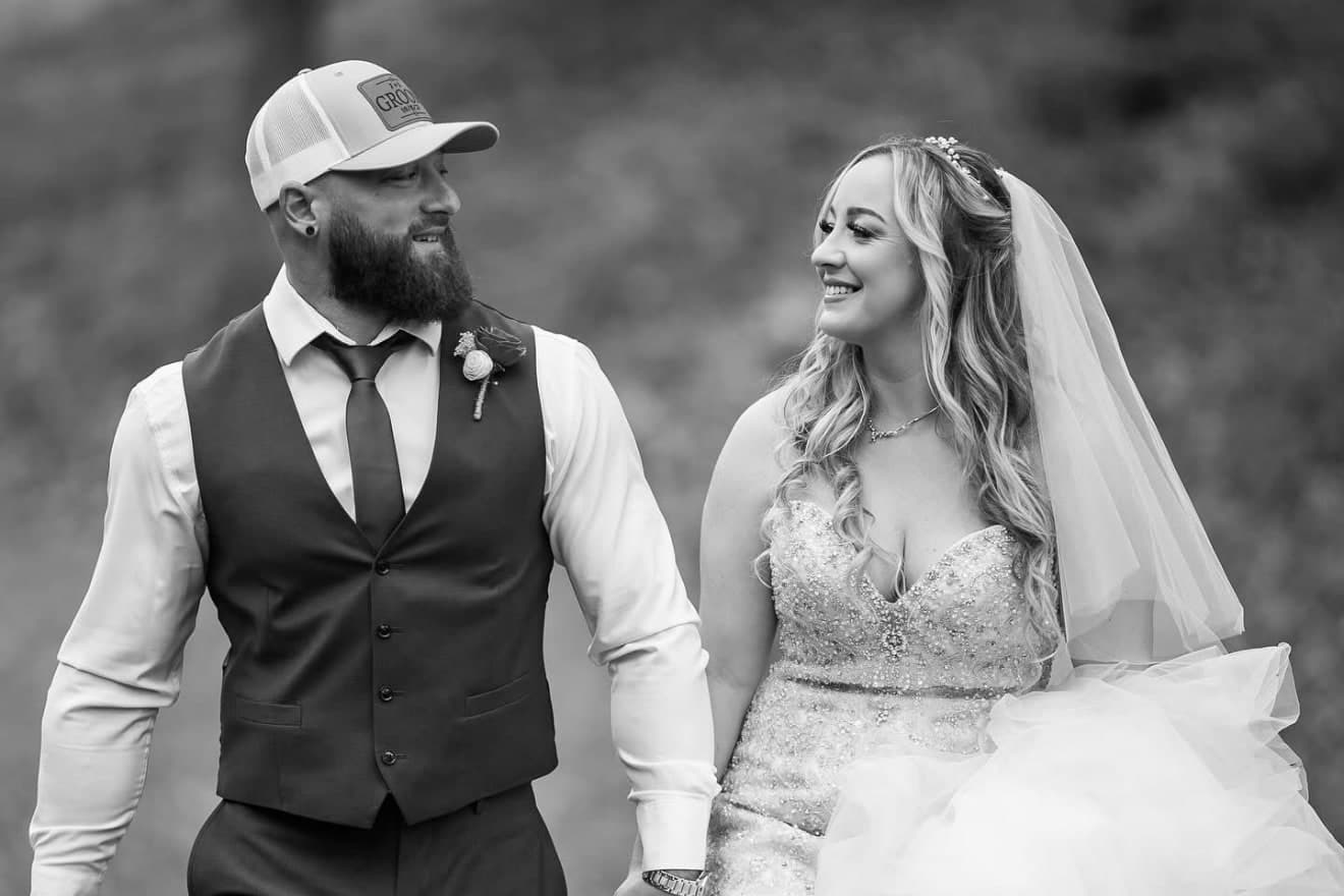Bride and groom smiling at each other as they walk hand in hand