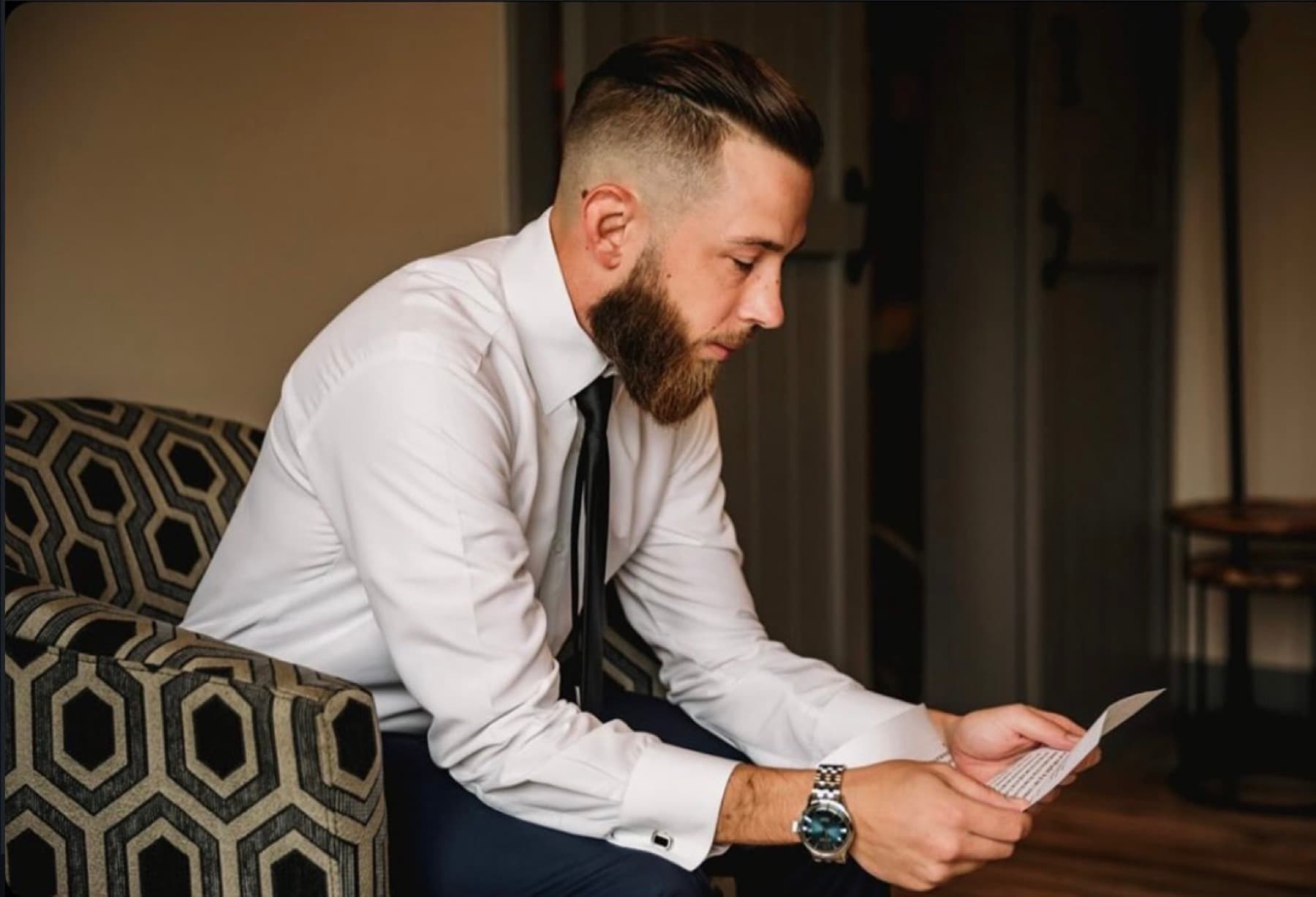 Groom with a fresh fade reading a letter before the ceremony