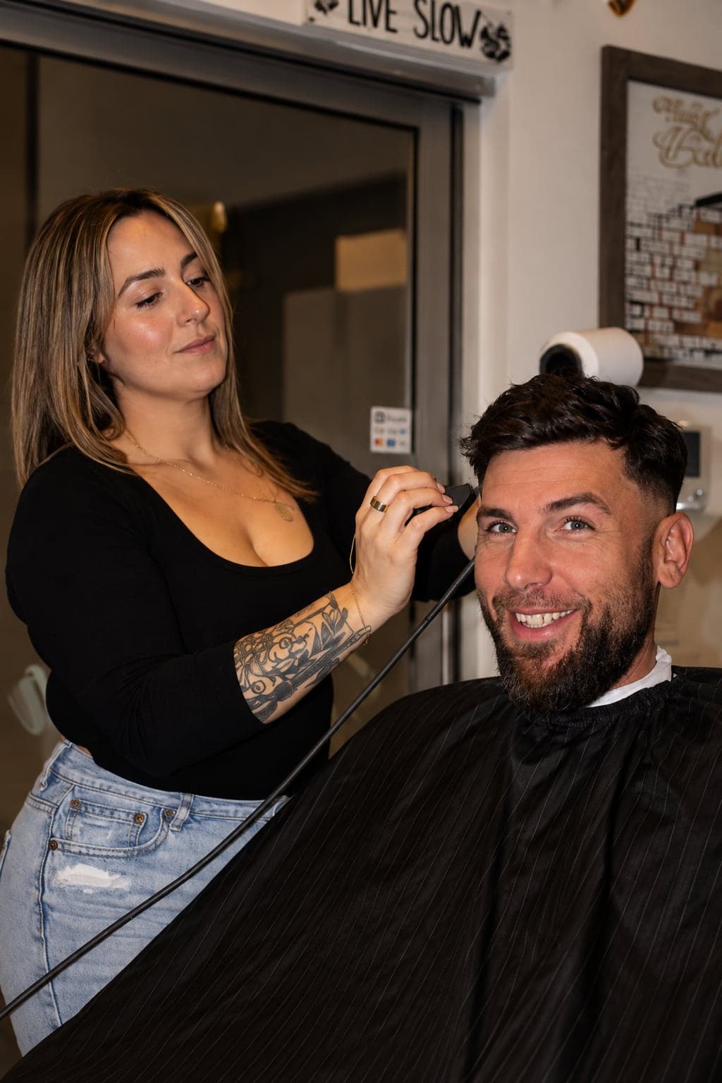Jenna cutting a smiling client's hair with clippers
