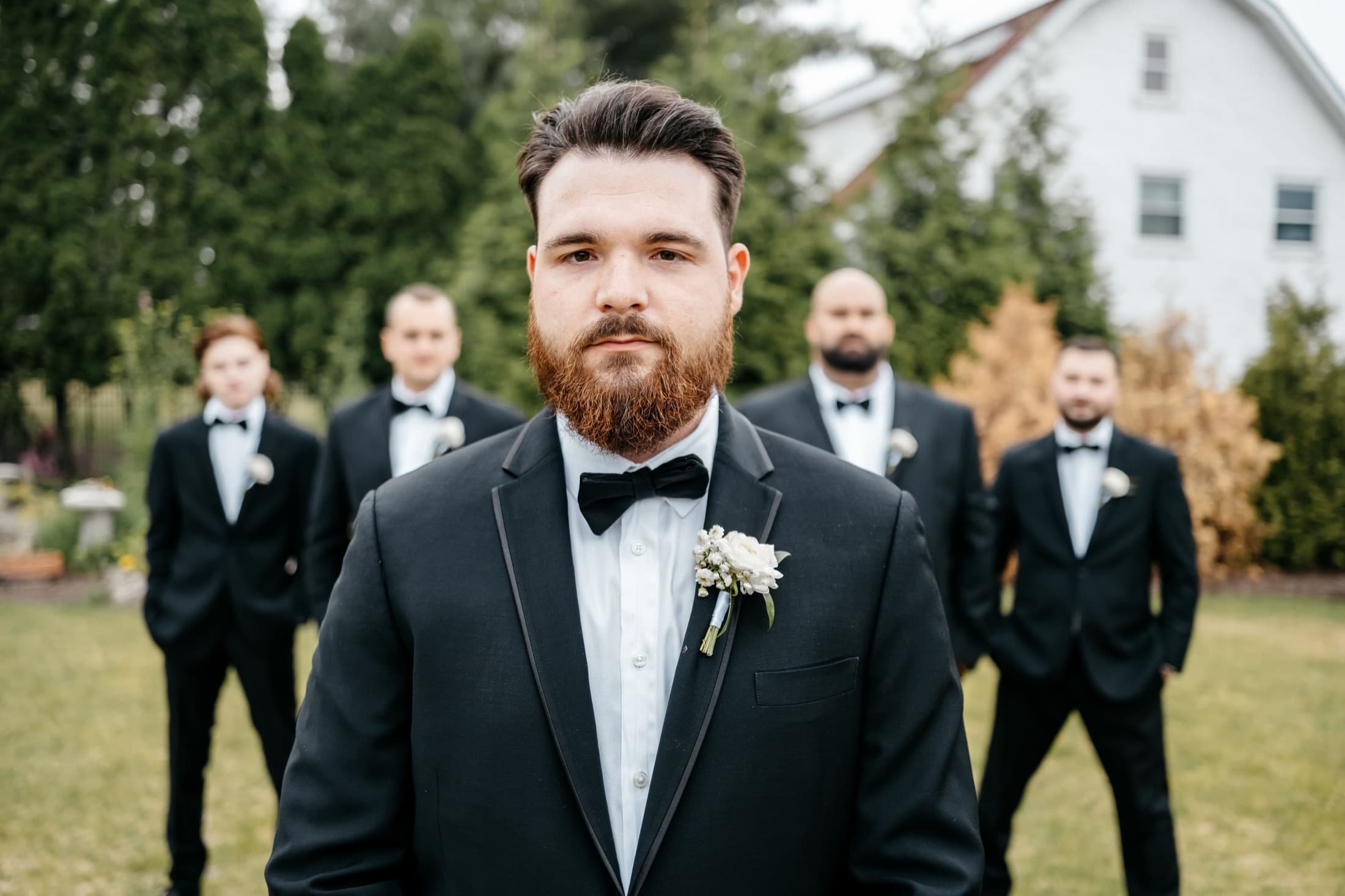 Groom in a tuxedo with his groomsmen behind him